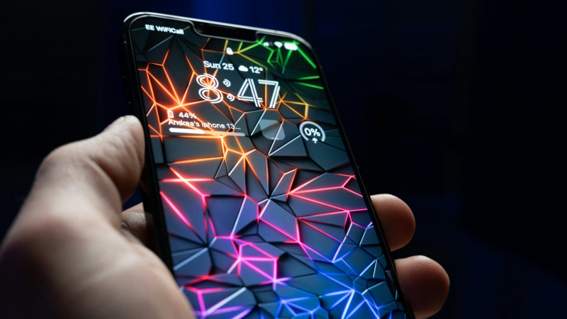   iPhone 13 Pro Maxを直接手に取る's hand, with cyberpunk artificial intelligence-themed wallpaper on the Lock Screen